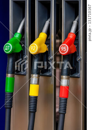Fuel pump nozzles at gas station with green diesel and yellow 92 and red 95 octane options 131710167