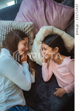 Sisters communicating on sofa in cozy home environment Sisters communicating on sofa in cozy home environment 131711437