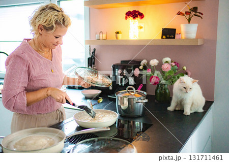 Woman cooking with cat in kitchen at home Woman cooking with cat in kitchen at home 131711461