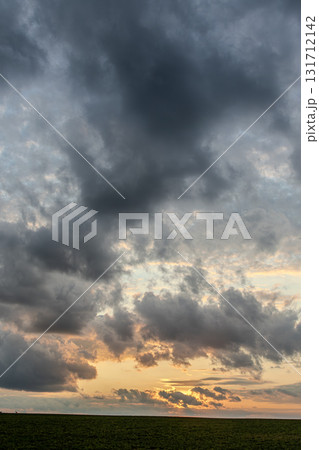 Dramatic sunset sky filled with clouds over a vast field at dusk capturing vibrant colors and natural beauty Dramatic sunset sky filled with clouds over a vast field at dusk capturing vibrant colors and natural beauty 131712142