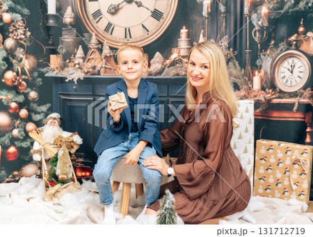 Cheerful mother and son enjoying time together near festive decorations, Christmas tree and glowing lights Cheerful mother and son enjoying time together near festive decorations, Christmas tree and glowing lights 131712719
