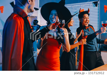 Joyful office Halloween party with coworkers in costumes, celebrating with drinks and laughter, fostering teamwork and festive spirit 131712912