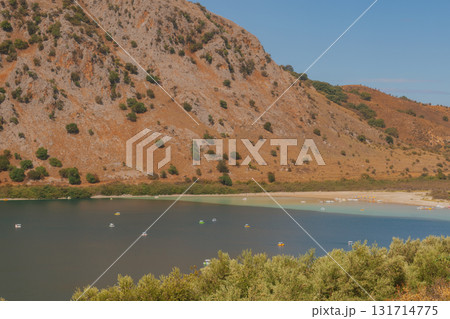 Drying mountain lake with wide strip of dried shore and orange rocky slope. 131714775