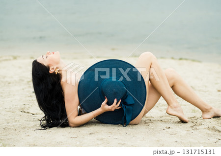 A young woman with long black hair is resting on the sand A young woman with long black hair is resting on the sand 131715131