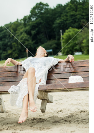 A beautiful woman with black hair sits on a swing over the sand, enjoying the view of nature 131715166