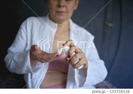 a senior woman in underwear on the bed performs routine self-care with face and body cosmetics, face foam a senior woman in underwear on the bed performs routine self-care with face and body cosmetics, face foam 131716116