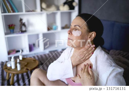 a senior woman in underwear on the bed performs routine self-care with body cosmetics a senior woman in underwear on the bed performs routine self-care with body cosmetics 131716131
