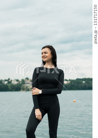 A beautiful woman with an athletic build poses against the backdrop of the water's surface A beautiful woman with an athletic build poses against the backdrop of the water's surface 131717150