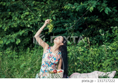A young girl is sitting on a pink rug and holding a bunch of green grapes in her hands 131717222