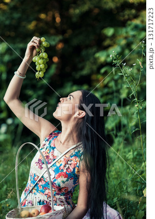 A young girl is sitting on a pink rug and holding a bunch of green grapes in her hands 131717223