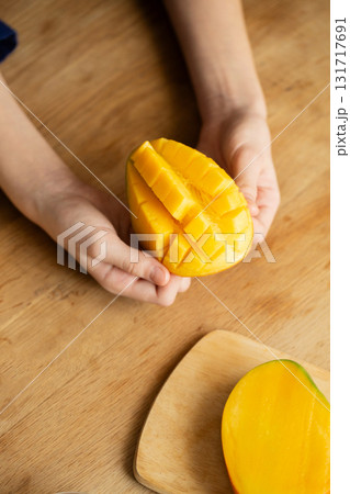 Hands holding fresh cut mango on wooden table vertical Hands holding fresh cut mango on wooden table vertical 131717691