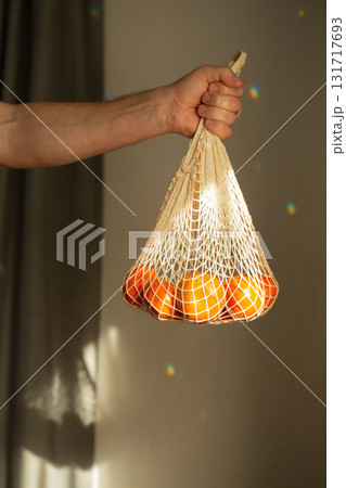 Hand holding eco-mesh bag with tangerines 131717693