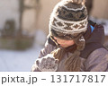 Boy in knitted winter hat holding snow in hands outdoors 131717817