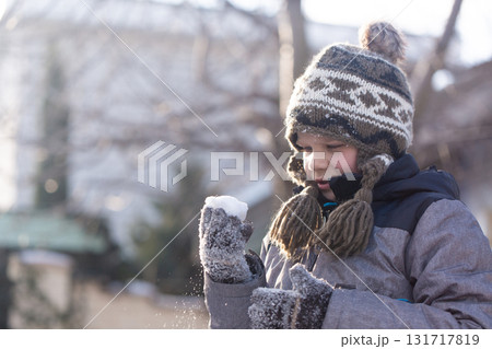 Boy observing snowball in his hands during winter outdoor play Boy observing snowball in his hands during winter outdoor play 131717819