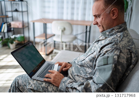 Soldier using laptop and credit card making online purchase at home 131717968