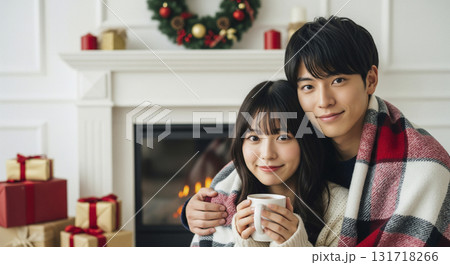 暖炉の前でブランケットに包まりながら寄り添う恋人たち 131718266