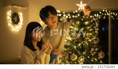 クリスマスツリーの飾り付けを楽しむ恋人たち 131718283