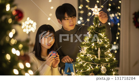 クリスマスツリーの飾り付けを楽しむ恋人たち クリスマスツリーの飾り付けを楽しむ恋人たち 131718284