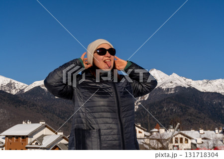 Woman Mountains Winter: Sunny day portrait, adjusting hat, snowy Alps backdrop. Woman Mountains Winter: Sunny day portrait, adjusting hat, snowy Alps backdrop. 131718304