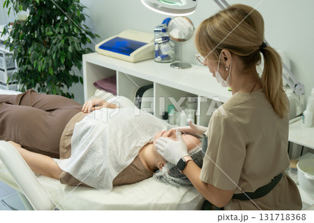 Cosmetology Treatment Facial Skincare Clinic: Professional performs facial treatment on client. 131718368