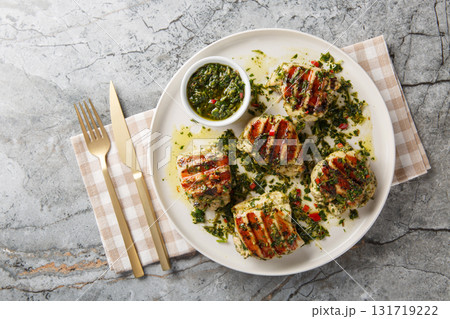 Grilled chicken thighs with chimichurri sauce made with garlic, herbs and vegetable oil close-up in a plate. Horizontal top view Grilled chicken thighs with chimichurri sauce made with garlic, herbs and vegetable oil close-up in a plate. Horizontal top view 131719222