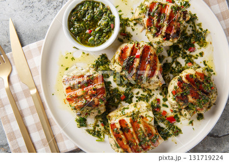 Chimichurri Chicken is marinated in homemade Chimichurri Sauce then grilled and topped with fresh sauce close-up in a plate. Horizontal top view Chimichurri Chicken is marinated in homemade Chimichurri Sauce then grilled and topped with fresh sauce close-up in a plate. Horizontal top view 131719224