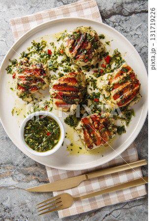Grilled chicken thighs with Argentinian chimichurri sauce closeup on the plate. Vertical top view Grilled chicken thighs with Argentinian chimichurri sauce closeup on the plate. Vertical top view 131719226