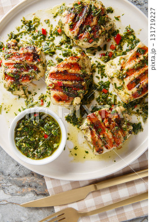Chimichurri chicken grilled to juicy perfection, and coated in a generous amount of fresh chimichurri sauce closeup on the plate. Vertical top view Chimichurri chicken grilled to juicy perfection, and coated in a generous amount of fresh chimichurri sauce closeup on the plate. Vertical top view 131719227