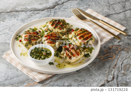 Grilled chicken thighs with chimichurri sauce made with garlic, herbs and vegetable oil close-up in a plate. Horizontal 131719228