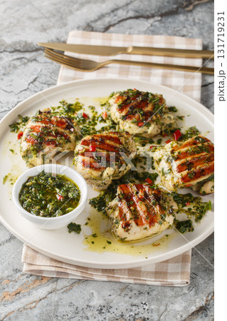Grilled chicken thighs with Argentinian chimichurri sauce closeup on the plate. Vertical Grilled chicken thighs with Argentinian chimichurri sauce closeup on the plate. Vertical 131719231