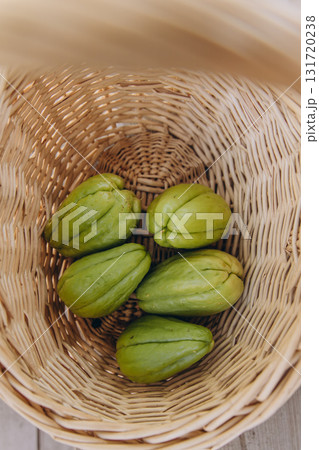 Several fresh green chayote fruits in a wicker basket top view. Organic tropical vegetable harvest. Healthy vegan food and sustainable farming concept Several fresh green chayote fruits in a wicker basket top view. Organic tropical vegetable harvest. Healthy vegan food and sustainable farming concept 131720238