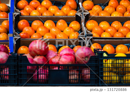 rows of ripe persimmons, pomegranates and lemons in wooden boxes on the market rows of ripe persimmons, pomegranates and lemons in wooden boxes on the market 131720886