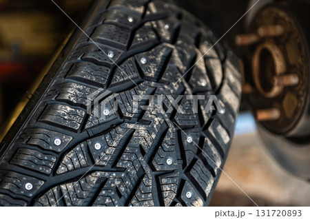 winter studded tires in the service near the car, seasonal tire change, close-up 131720893