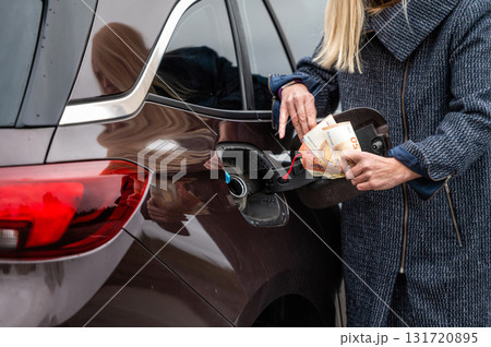 woman with banknotes near car, put money to car tank, the concept of rising fuel prices, closeup woman with banknotes near car, put money to car tank, the concept of rising fuel prices, closeup 131720895