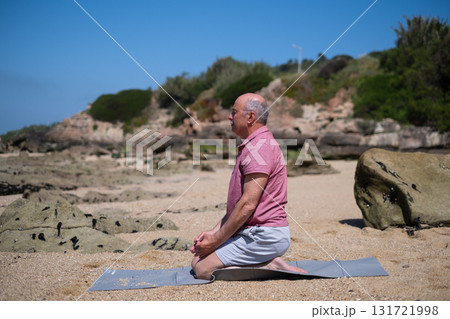 Elderly man sitting on the beach meditating and doing yoga Elderly man sitting on the beach meditating and doing yoga 131721998