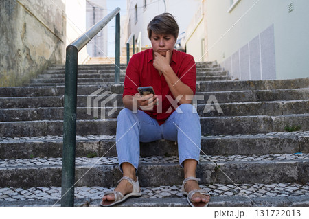 Sad woman sitting on stairs with a phone. no signal, no money, or afraid to call her boyfriend 131722013