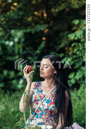 A lady in a light floral dress sits on a pink rug surrounded by nature A lady in a light floral dress sits on a pink rug surrounded by nature 131722159
