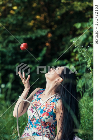A seductive girl in a floral dress sits on a pink rug at a picnic 131722163