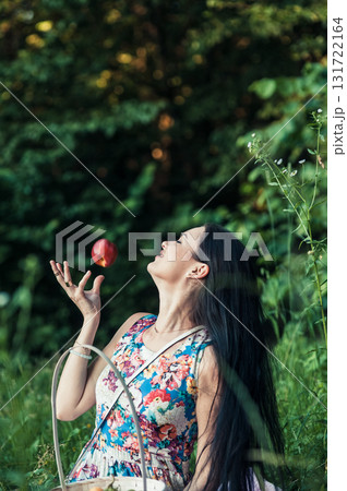 A seductive girl in a floral dress sits on a pink rug at a picnic 131722164