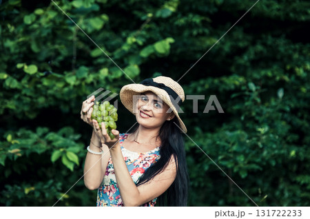 A young girl holds a bunch of green grapes 131722233