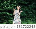 A young girl stands in the green forest with two red apples in her hands 131722248