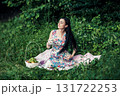 A lady in a cute dress sitting with a cup of tea among the greenery of the park 131722253