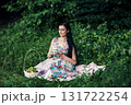 A lady in a cute dress sitting with a cup of tea among the greenery of the park 131722254