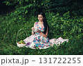 A lady in a cute dress sitting with a cup of tea among the greenery of the park 131722255