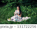 A woman in a floral outfit holds a cup of aromatic coffee at a picnic 131722256