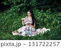 A woman in a floral outfit holds a cup of aromatic coffee at a picnic 131722257