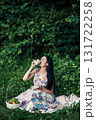 A woman in a floral outfit holds a cup of aromatic coffee at a picnic 131722258