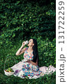 A young girl sits among the greenery of the forest with a cup of tea in her hands 131722259