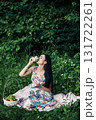 A young girl sits among the greenery of the forest with a cup of tea in her hands 131722261