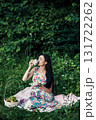 A young girl sits among the greenery of the forest with a cup of tea in her hands 131722262
